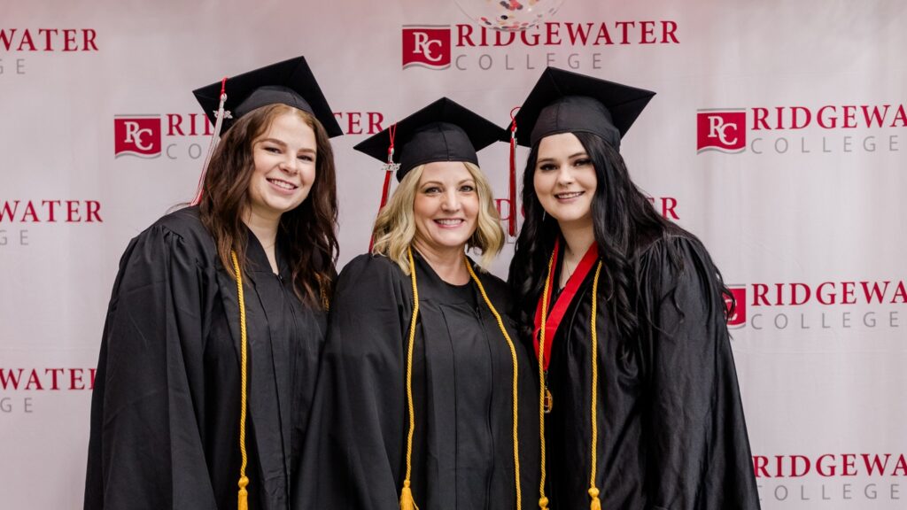 Three Ridgewater graduates wearing their cap and gown.